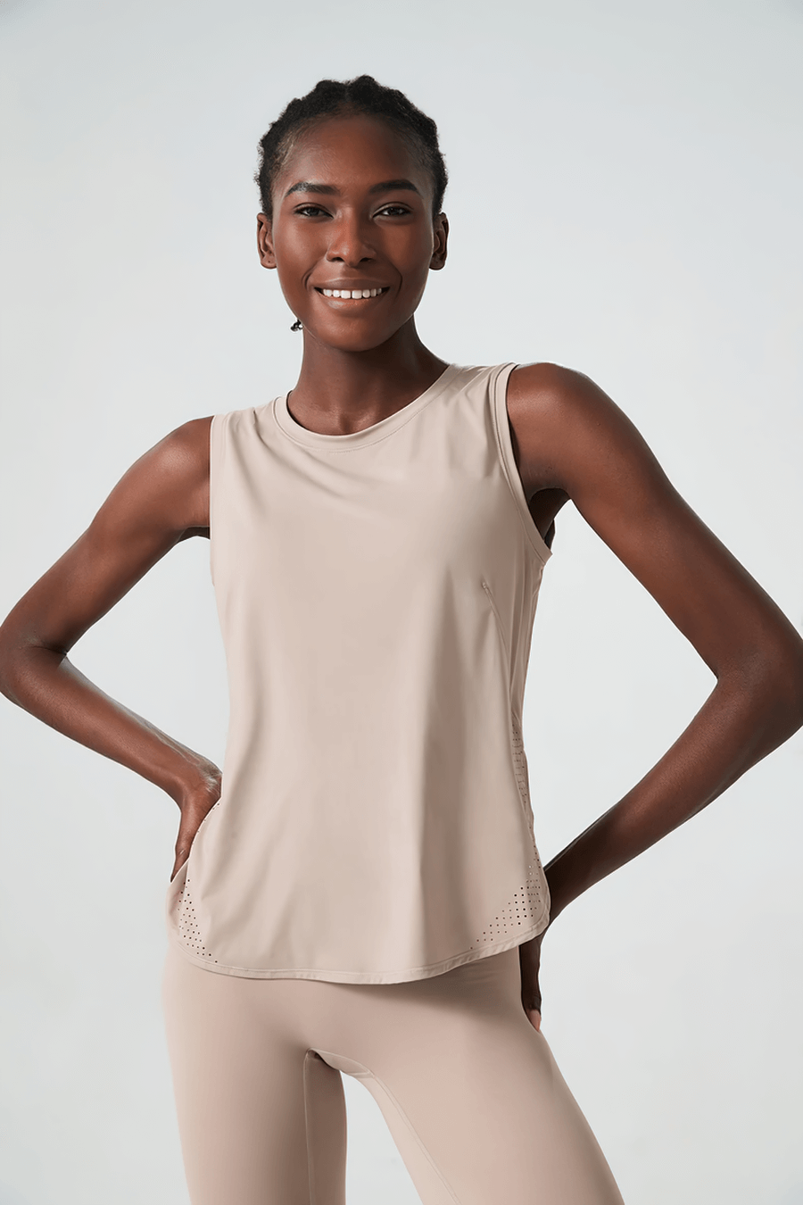 Woman wearing beige activewear tank top, perfect for running and yoga. Stylish and functional workout gear for active lifestyles.